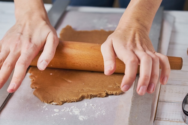 Female hands rolling dough on table. closeup. Woman making dough for baking in the kitchen