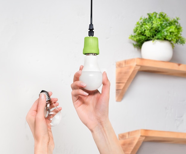 Female hands screw in an energysaving LED light bulb