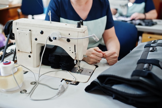 Female hands stitching fabric on professional manufacturing machine at workplace. Sewing process.