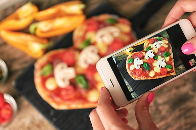 Female hands taking picture of tasty pizza