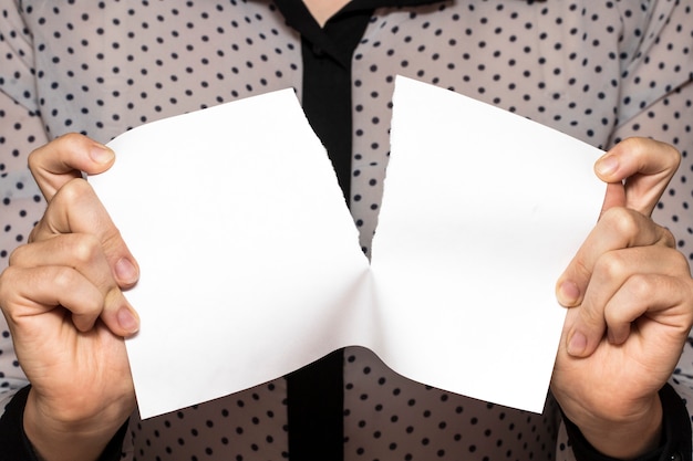 Female hands tearing a sheet of paper