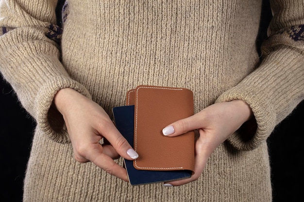 In female hands there is a brown purse and a passport