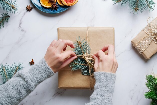 Female hands tie a bow on box with Christmas gift