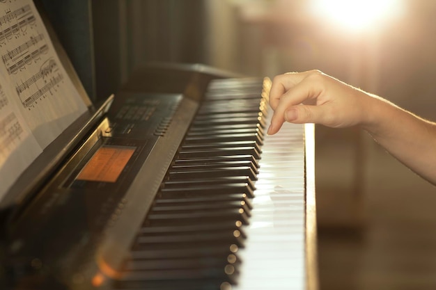 female hands touch the piano keys play a melody in the rays of the setting sun