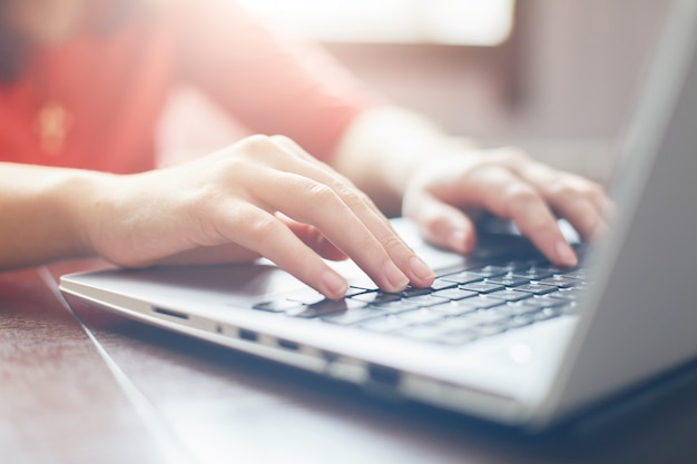 Female hands typing on keyboard of laptop surfing Internet and texting friends via social networks