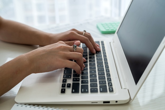 Female hands typing on laptop keyboard close up .