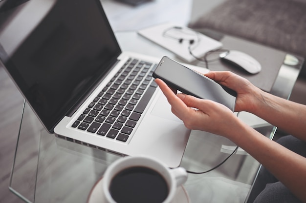 Female hands using smart phone in interior workplace, freelance business woman using cell phone at office desk, working from home using smart phone and notebook computer. Remote worker quarantine