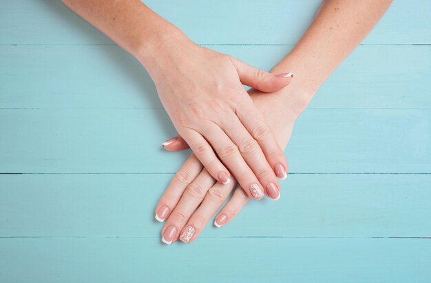 Female hands with beautiful manicure on a background of blue boards