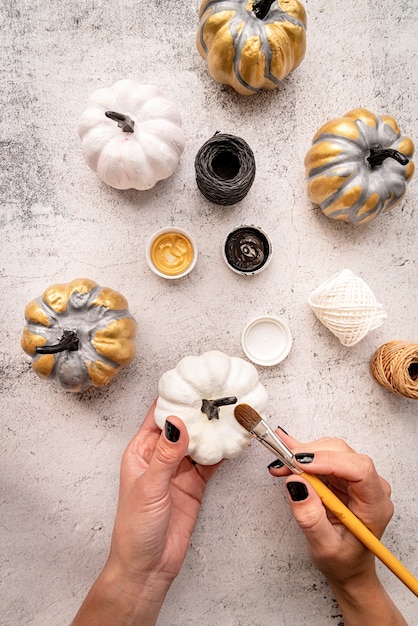 Female hands with black nails painting pumpkins for halloween