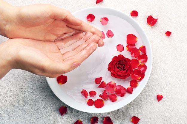 Female hands with bowl of aroma spa water on table closeup