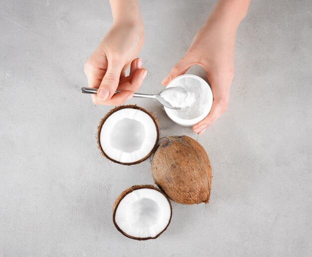 Photo female hands with coconut oil on grey background