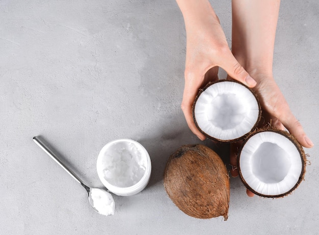 Photo female hands with coconuts and oil on grey background