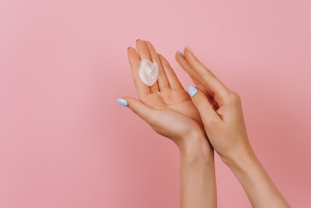 Female hands with cream isolated on pink