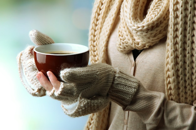 Female hands with hot drink, on light background