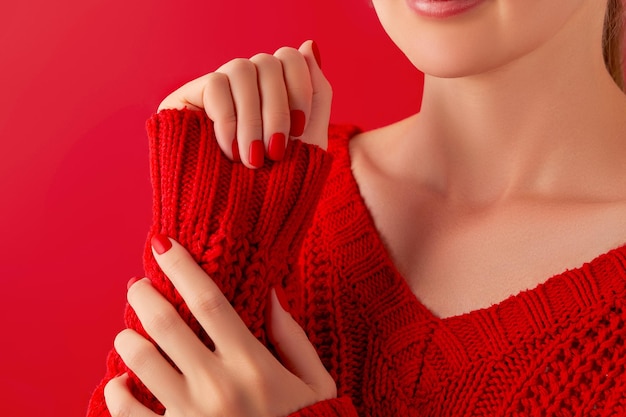 Female hands with manicure in sweater Red matt nail design