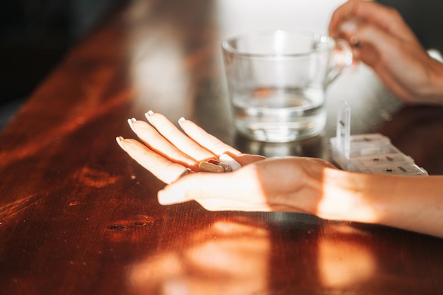 Female hands with omega 3 vitamin D capsules with glass of water