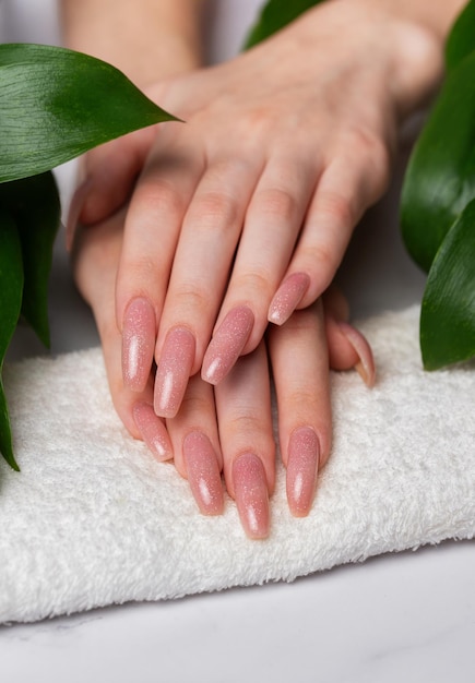 Female hands with pink nail design and green leaves