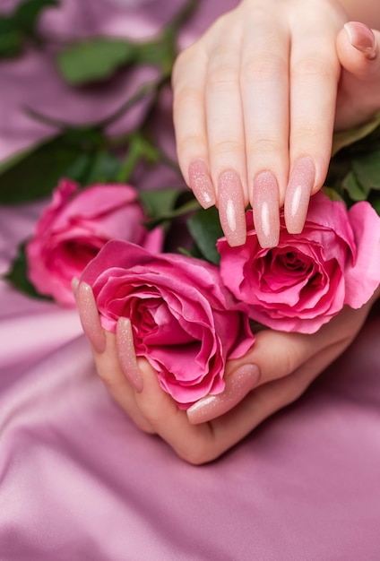 Female hands with pink nail design hold pink roses