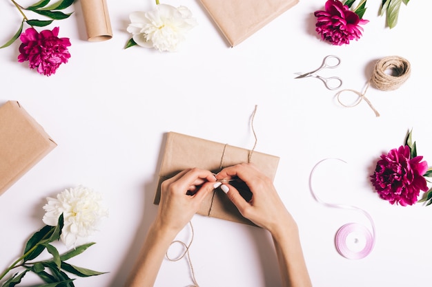 Female hands wrapping gifts on white table