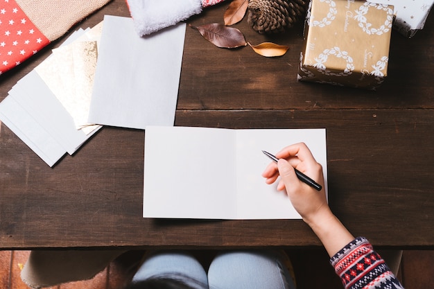 Female hands writing Christmas cards on wooden table