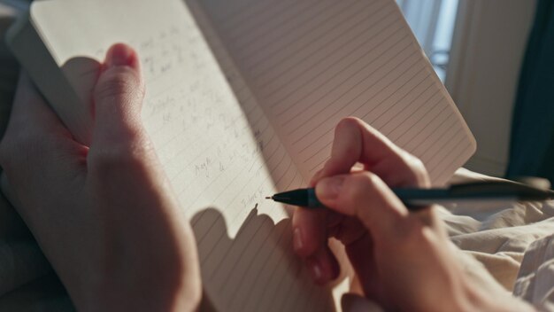 Photo female hands writing diary in sunlight closeup woman making notes in morning