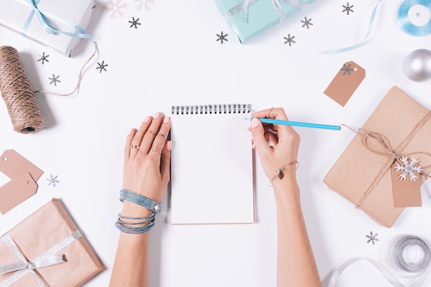 Female hands writing in a notebook among Christmas decorations