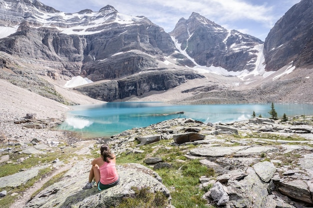 Female hiker sitting on the bank of turquoise glacier lake in beautiful alpine environment