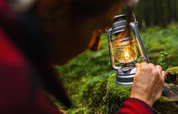 Photo female hiker using a kerosene lamp or oil lantern in the dark forest