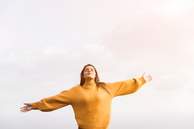 A female hiker with her arms outstretched enjoying the fresh air against sky