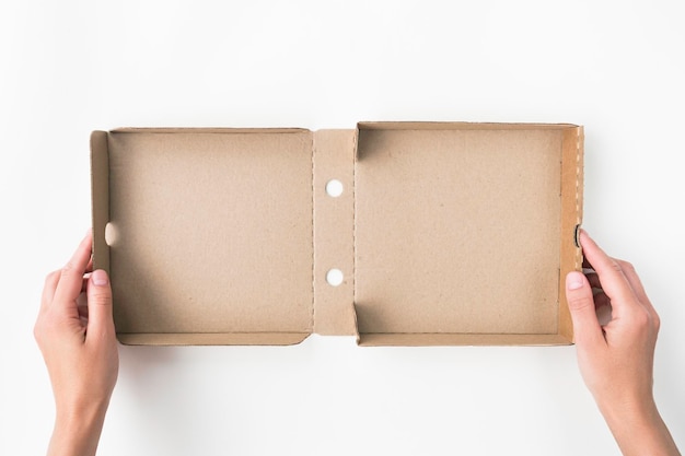 Female holding small opened empty cardboard pizza box on a white table background top view