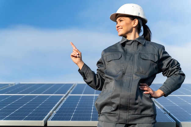 Female industrial technician in uniform near the energy batteries in the countryside