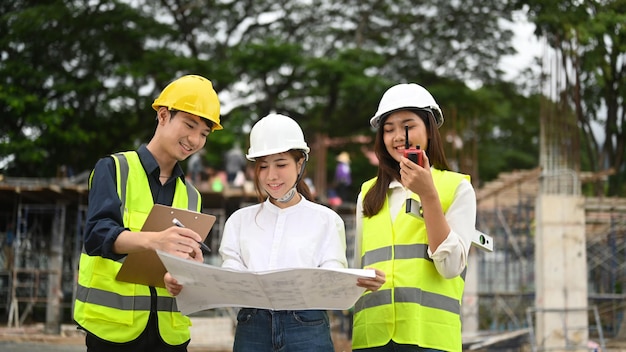 Female investor and engineers discussing planning development details together at construction site