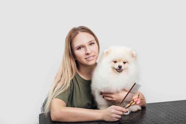 Female is grooming and trimming pomeranian spitz in salon