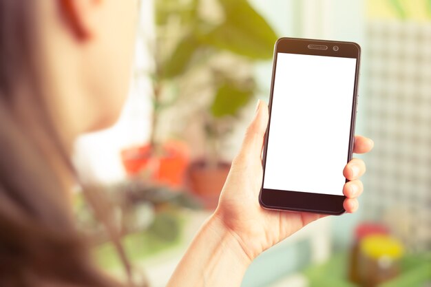 A female is holding a smartphone with a white screen. 