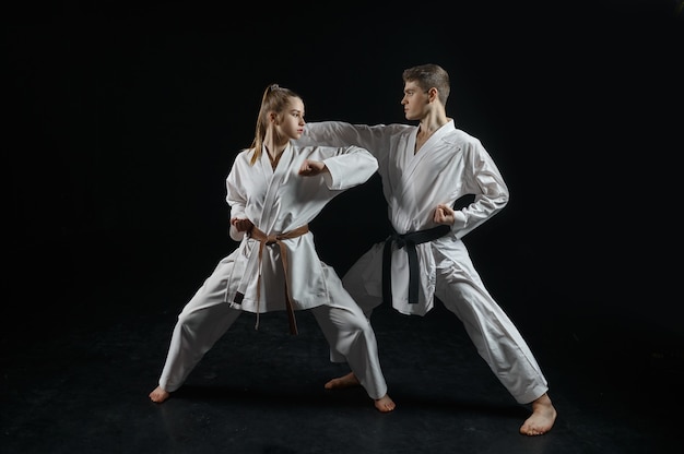 Female karate fighter on training with master, white kimono. Karateka on workout, martial arts, fighting