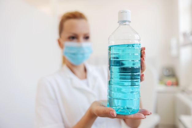 Female lab assistant holding blue liquid in her hands.