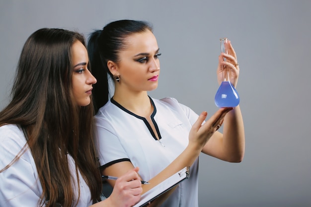 Female laboratory staff conducting an experiment with liquids in flasks. Research and science.