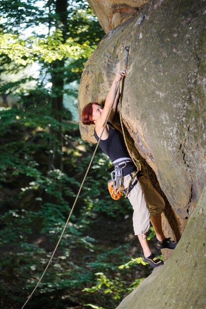 Female lead climber climbing on large boulder