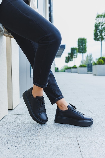 Female legs in black jeans and black laceup shoes Black leather shoes closeup