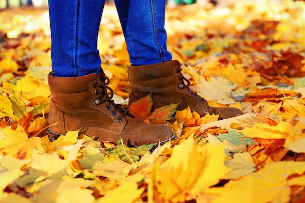 Female legs in boots on autumn leaves