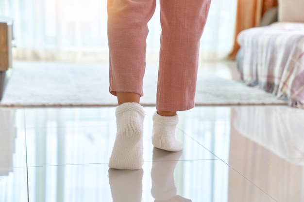 Female legs in cozy comfortable soft knitted socks on a warm heated floor in living room at home