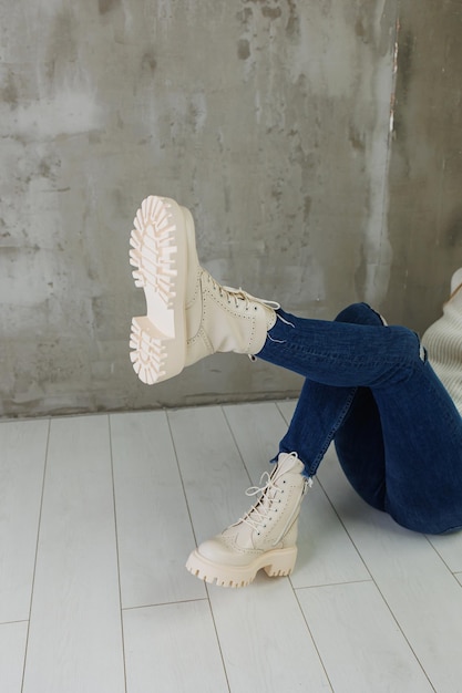 Female legs in jeans and white leather boots made of natural leather A collection of women's spring modern shoes