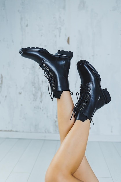 Female legs in leather black autumn boots A fashion girl stands in a store and measures shoes