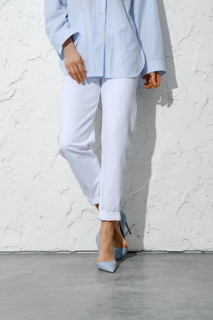 Female legs in white jeans blue shirt and stilettos