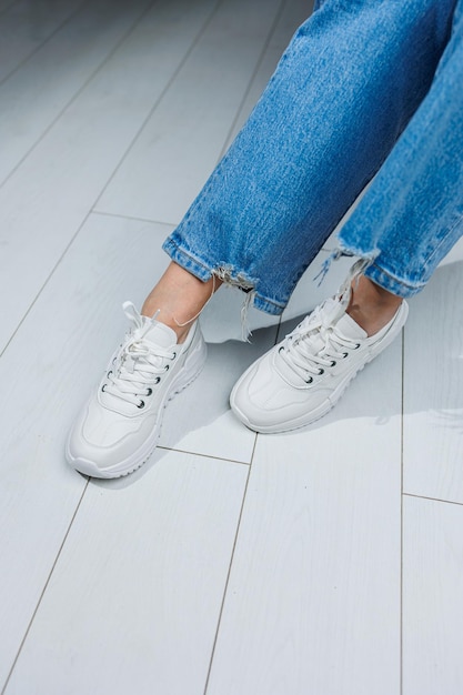 Female legs in white stylish sneakers Casual women's fashion Comfortable shoes for women Women's comfortable summer shoes