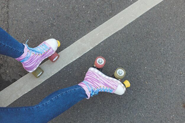 Female legs with rollerskates on asphalt background top view concept street active life