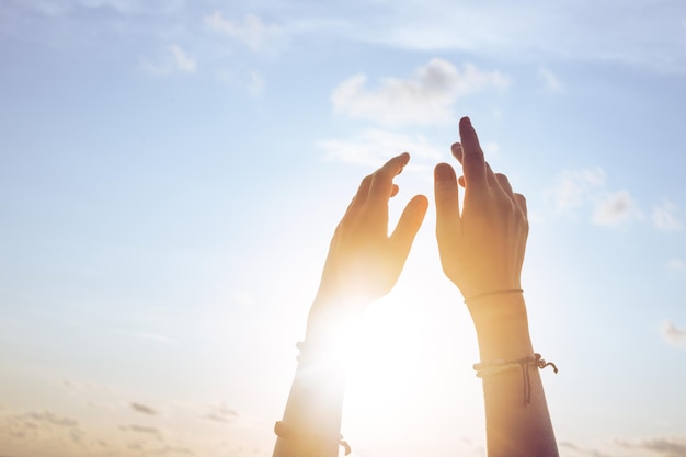 Female lifting hands up to sunset sky on blue sky