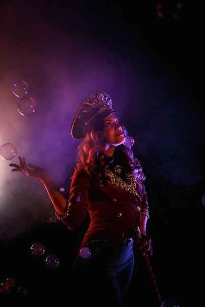 Female magician illusionist circus with stylish hat in shows soap bubbles show at black background