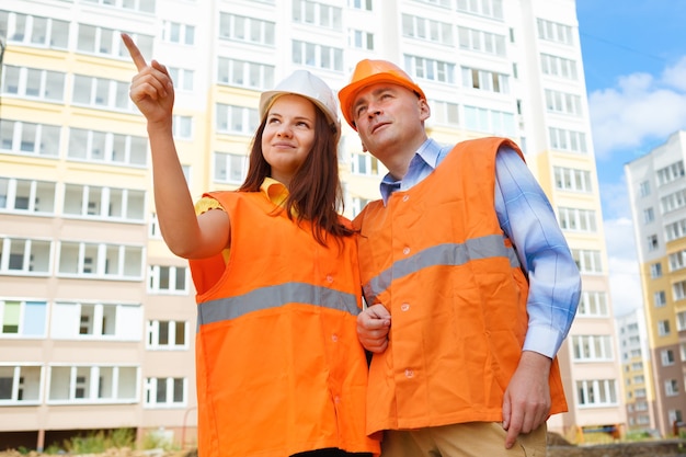 Female and male construction workers look up