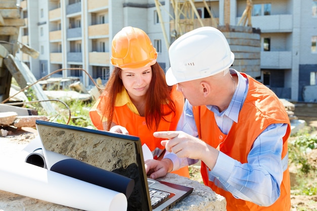 Female and male construction workers looking at laptop and smili